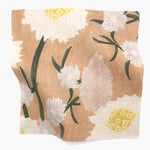 Square fabric swatch in a playful floral print in shades of pink, white, yellow and green on a coral field.