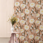 A mauve end table stands in front of a fabric curtain in a playful floral print in pink, white, yellow and green.