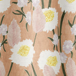 Draped fabric in a playful floral print in shades of pink, white, yellow and green on a coral field.