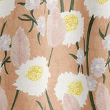 Draped fabric in a playful floral print in shades of pink, white, yellow and green on a coral field.
