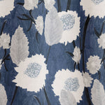 Draped fabric in a playful floral print in shades of white and gray on a navy field.