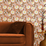 A couch and end table stand in front of a wall papered in a playful floral print in white, yellow, green and pink.