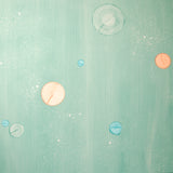 Detail of a wallpaper in a paint splatter print in metallic multicolor pastels on a green field.