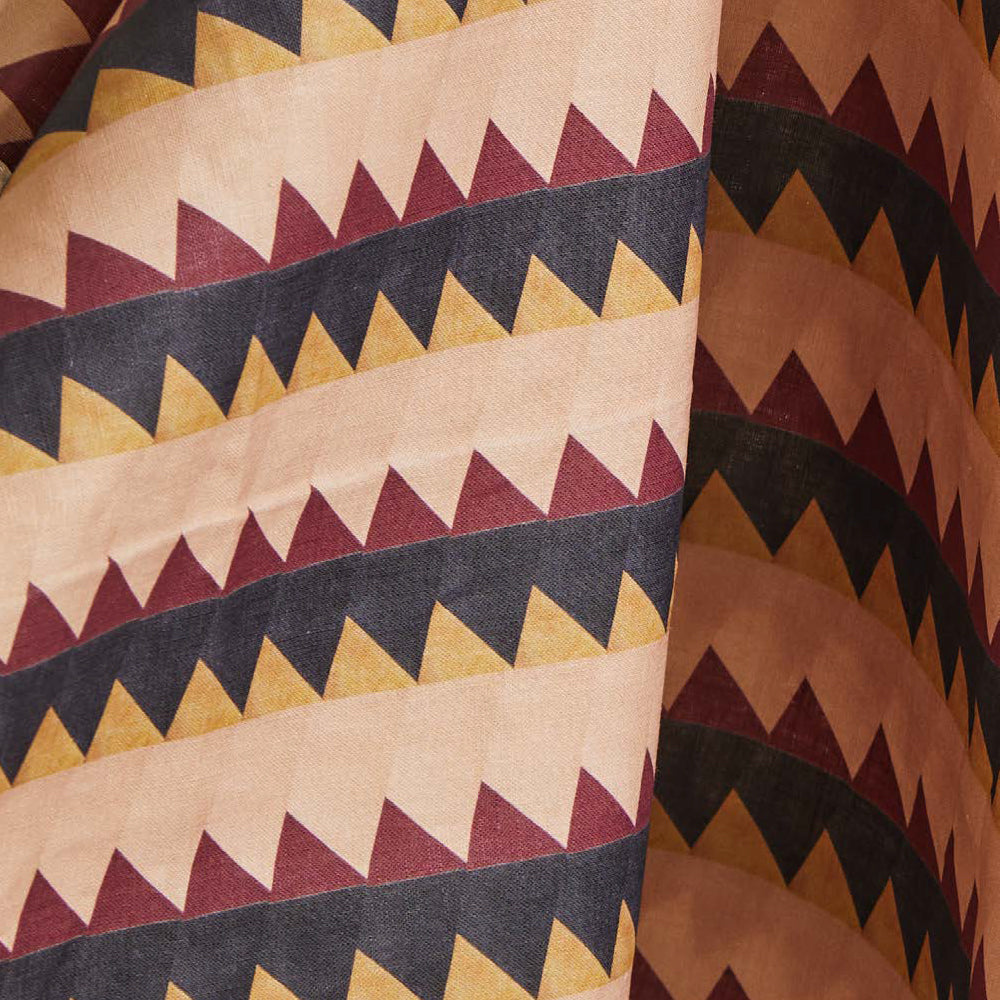 Draped fabric yardage in a striped triangle print in shades of peach, maroon and black.