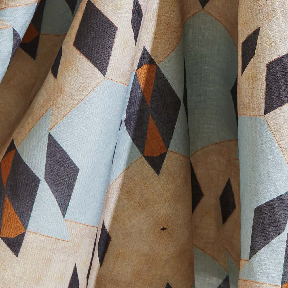 Draped fabric yardage in a striped triangle print in shades of tan, blue, navy and cream.