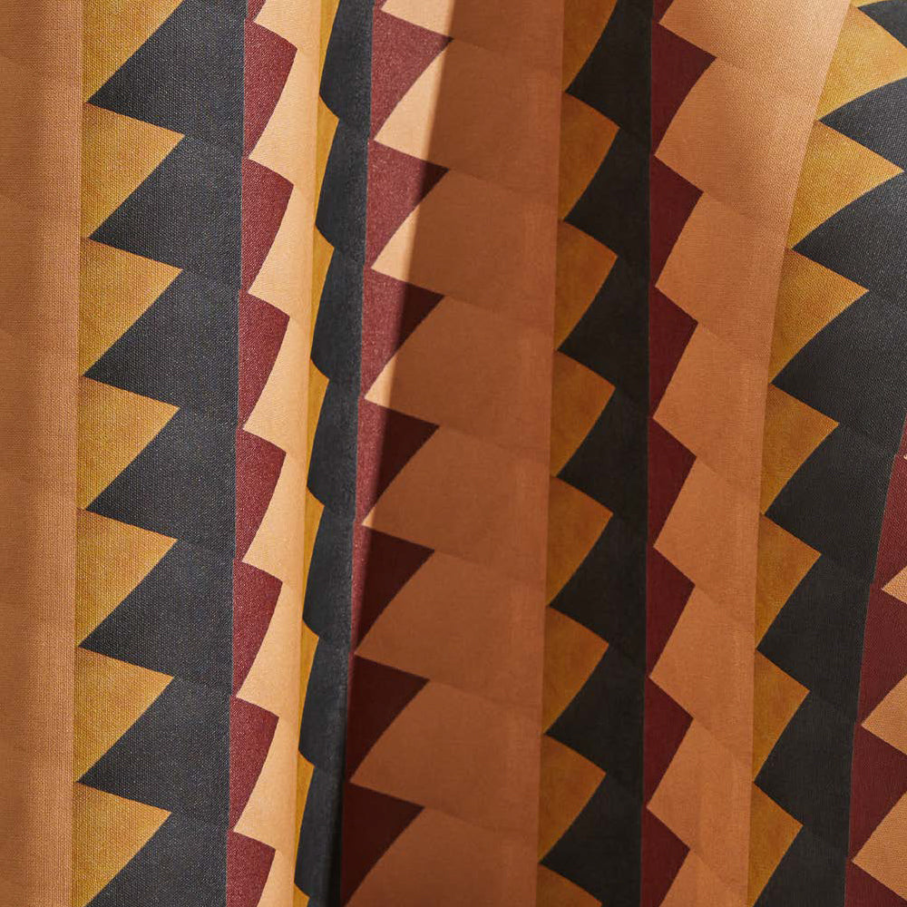 Draped wallpaper yardage in a large-scale triangle print in shades of orange, red and black.