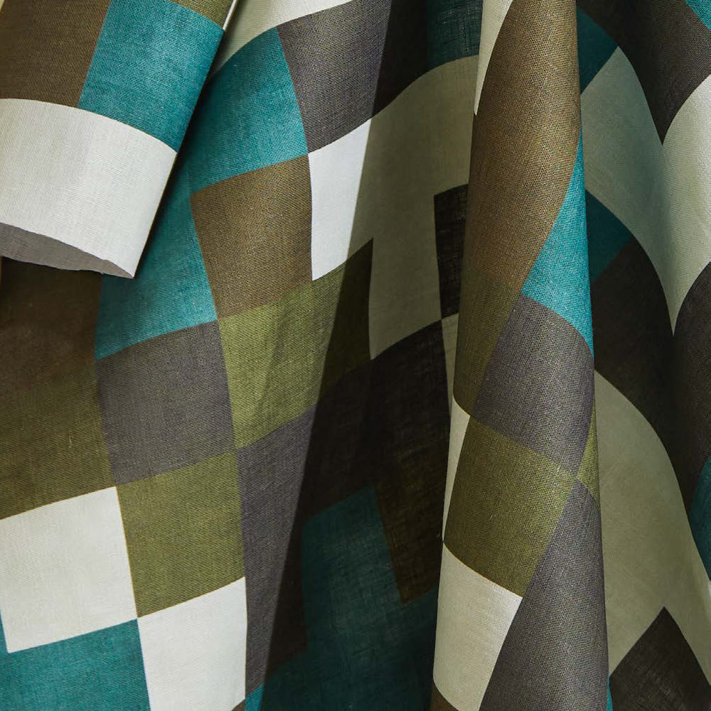Draped fabric yardage in an interlocking square pattern in shades of blue, green, gray and cream.