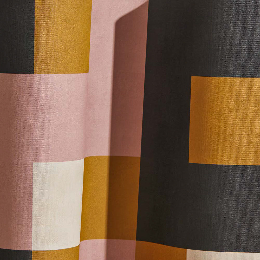 Draped wallpaper yardage in an interlocking square pattern in shades of mustard, pink and gray.