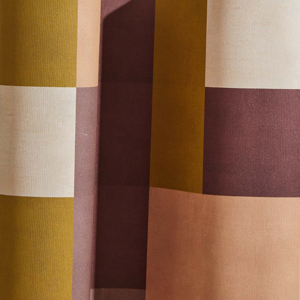 Draped wallpaper yardage in an interlocking square pattern in shades of mustard, purple and pink.