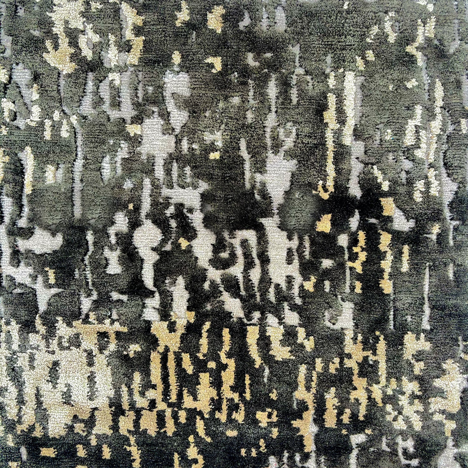 Detail of a silk rug in black, cream and charcoal in an abstract textural pattern.