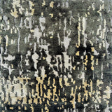 Detail of a silk rug in black, cream and charcoal in an abstract textural pattern.