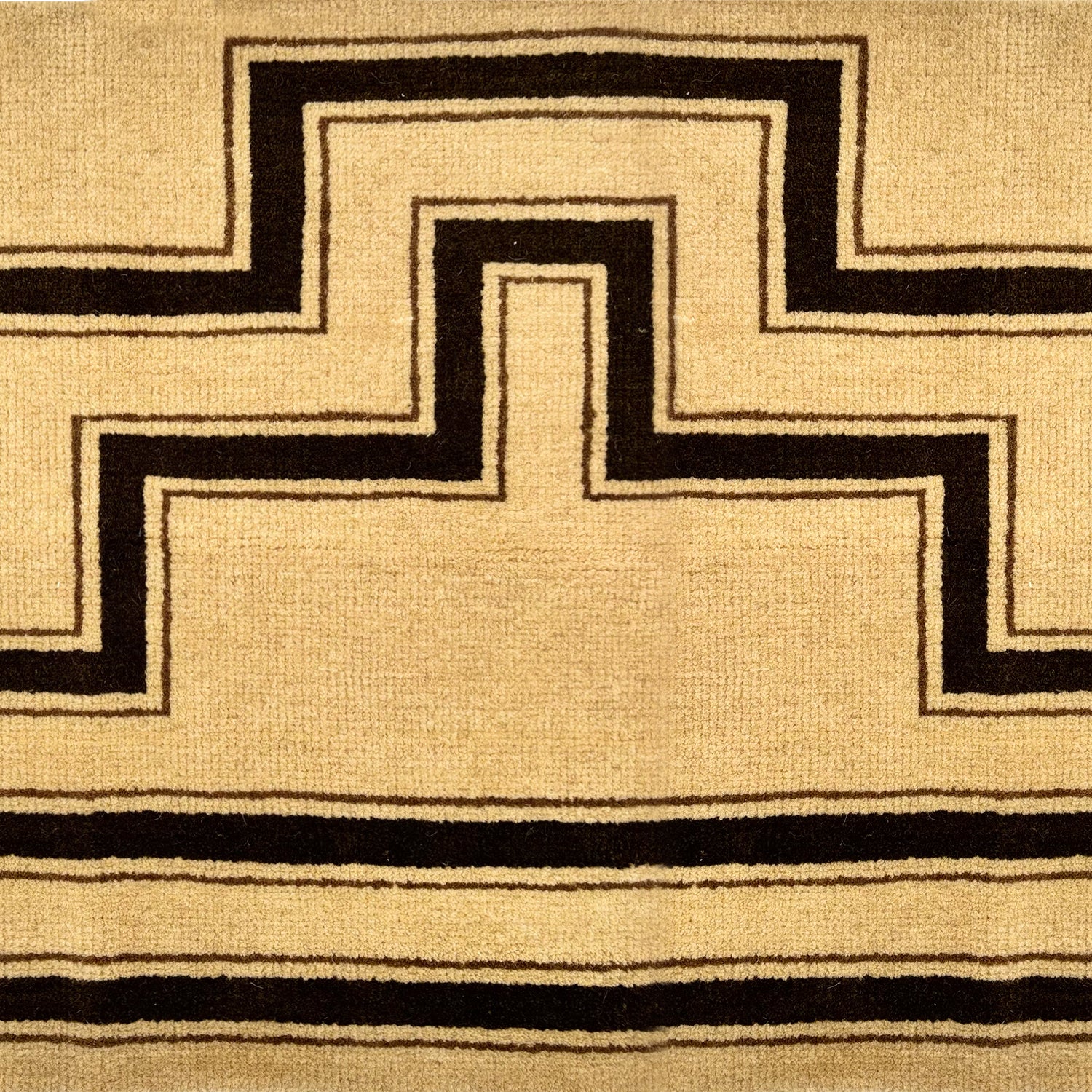 Detail of a handknotted rug with a geometric stripe pattern in brown on a cream field.