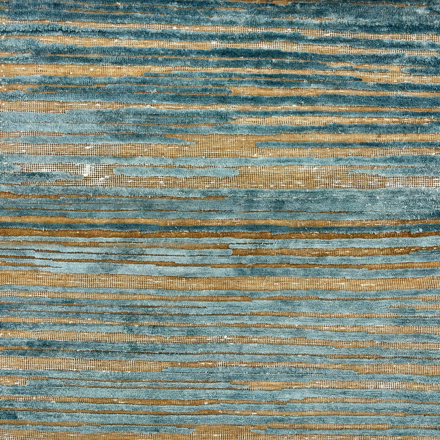 Detail of a wool rug with a textural strié pattern in teal and brown
