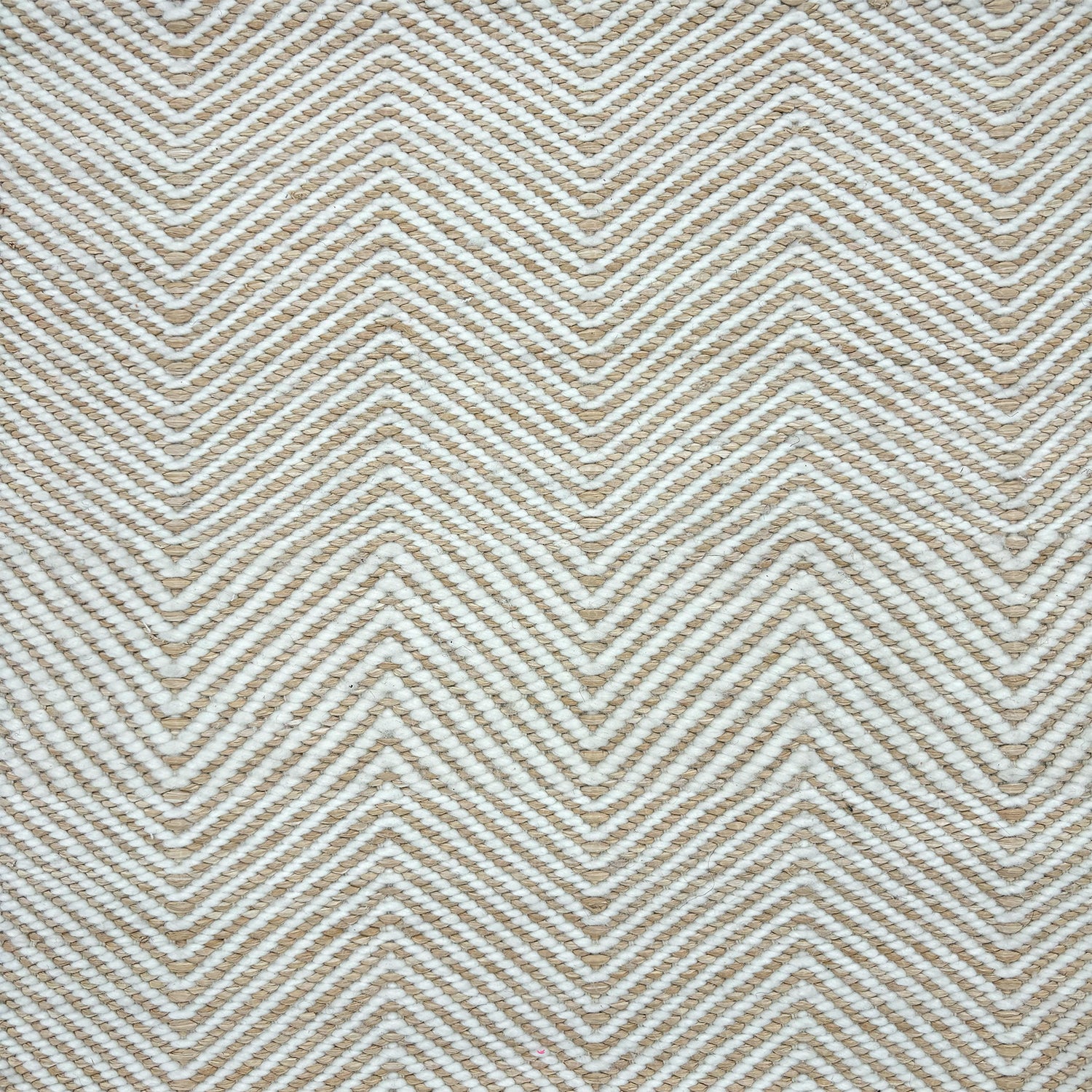 Detail of a handwoven rug in a chevron pattern in natural raffia and ivory yarn