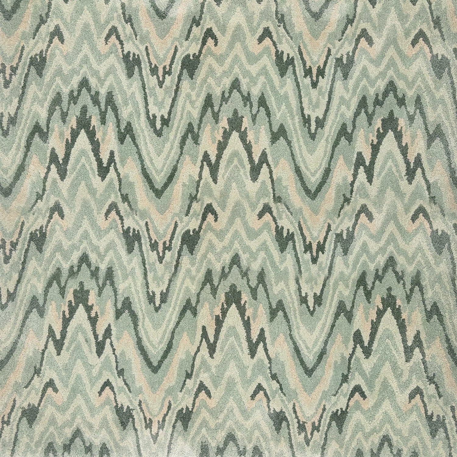 Detail of a handtufted rug with a flamestitch pattern in soft shades of green. 