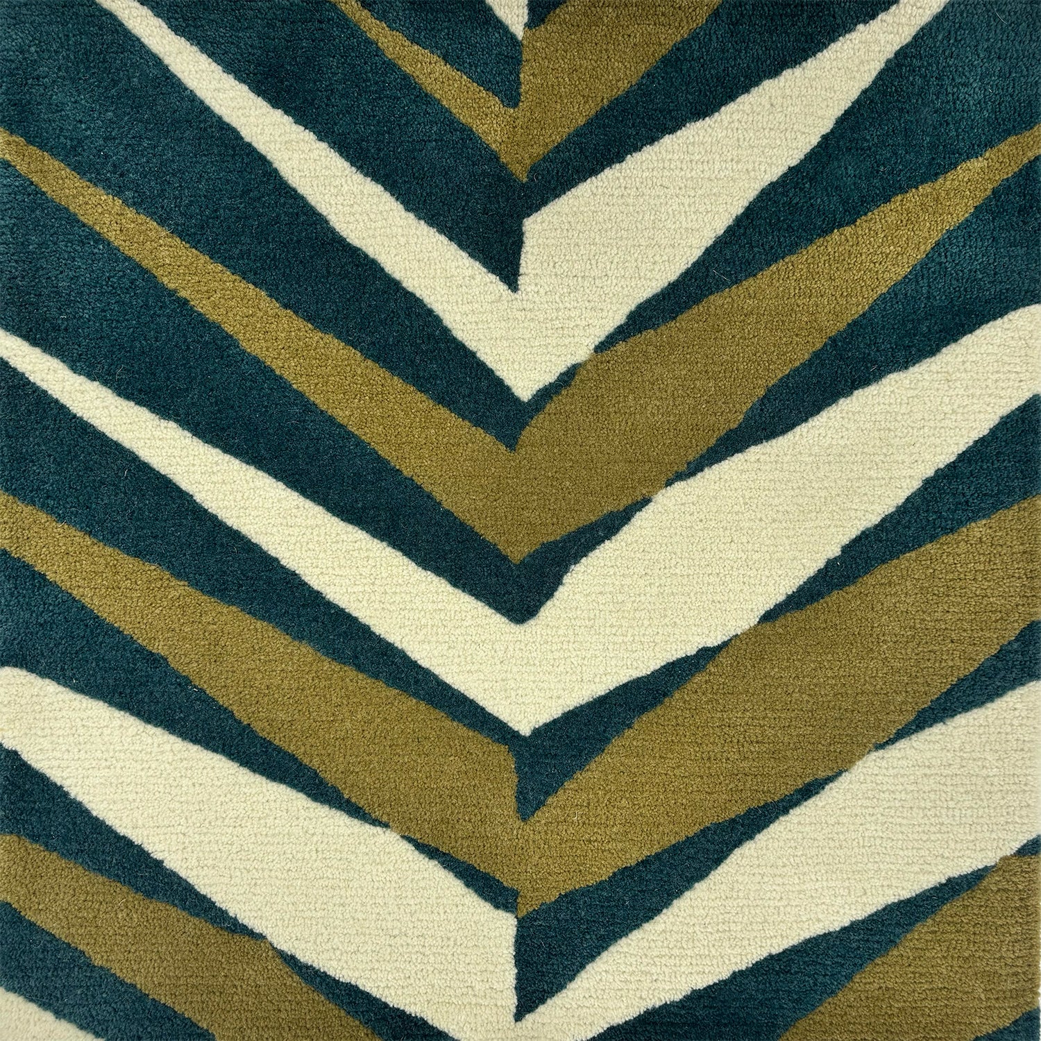 Detail of a handknotted rug in a large playful herringbone pattern in teal, cream and light green