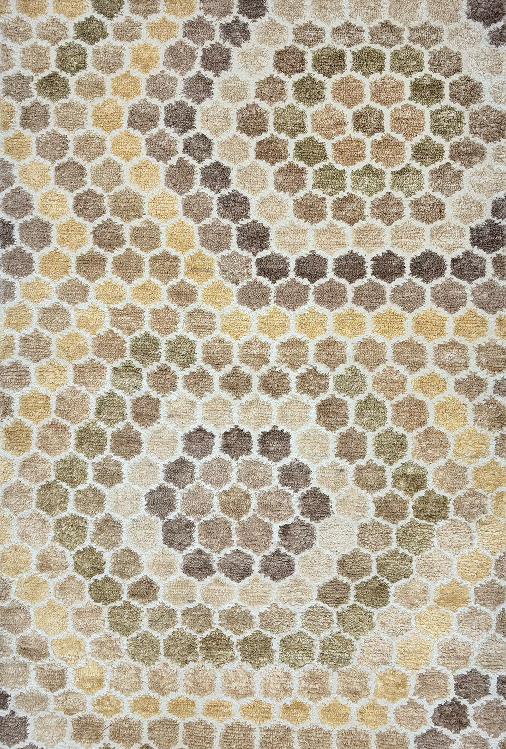 Detail of a handknotted rug with a classic hexagon pattern in shades of tan, yellow, white and oatmeal. 