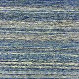 Detail of a wool rug with a textural strié stripe pattern in indigo and cream