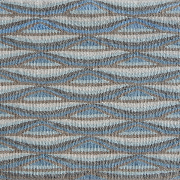 Detail of handwoven rug in a wavy striped pattern in shades of blue and tan.