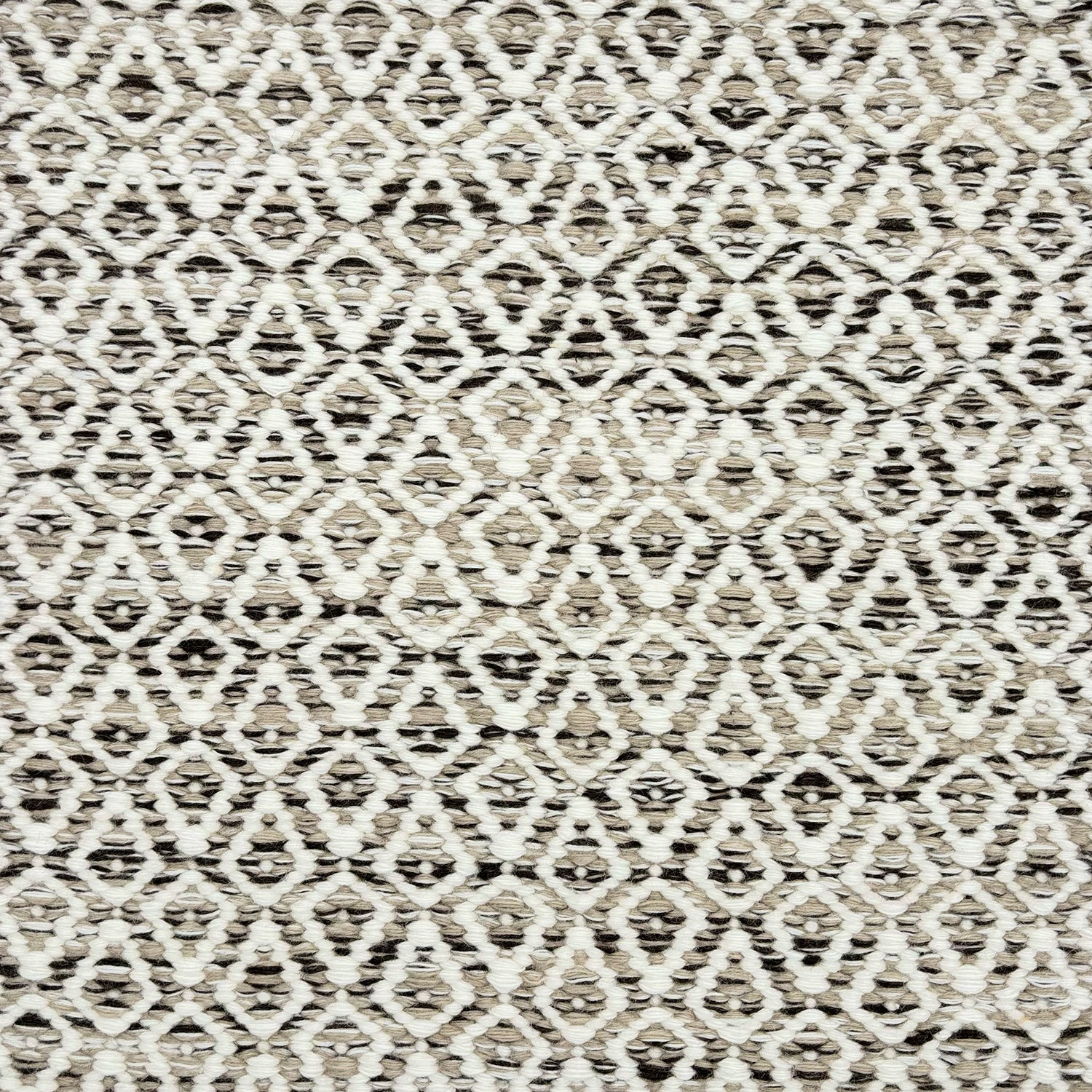 Detail of a handowven rug in an diamond like pattern in white and beige with grey accents.