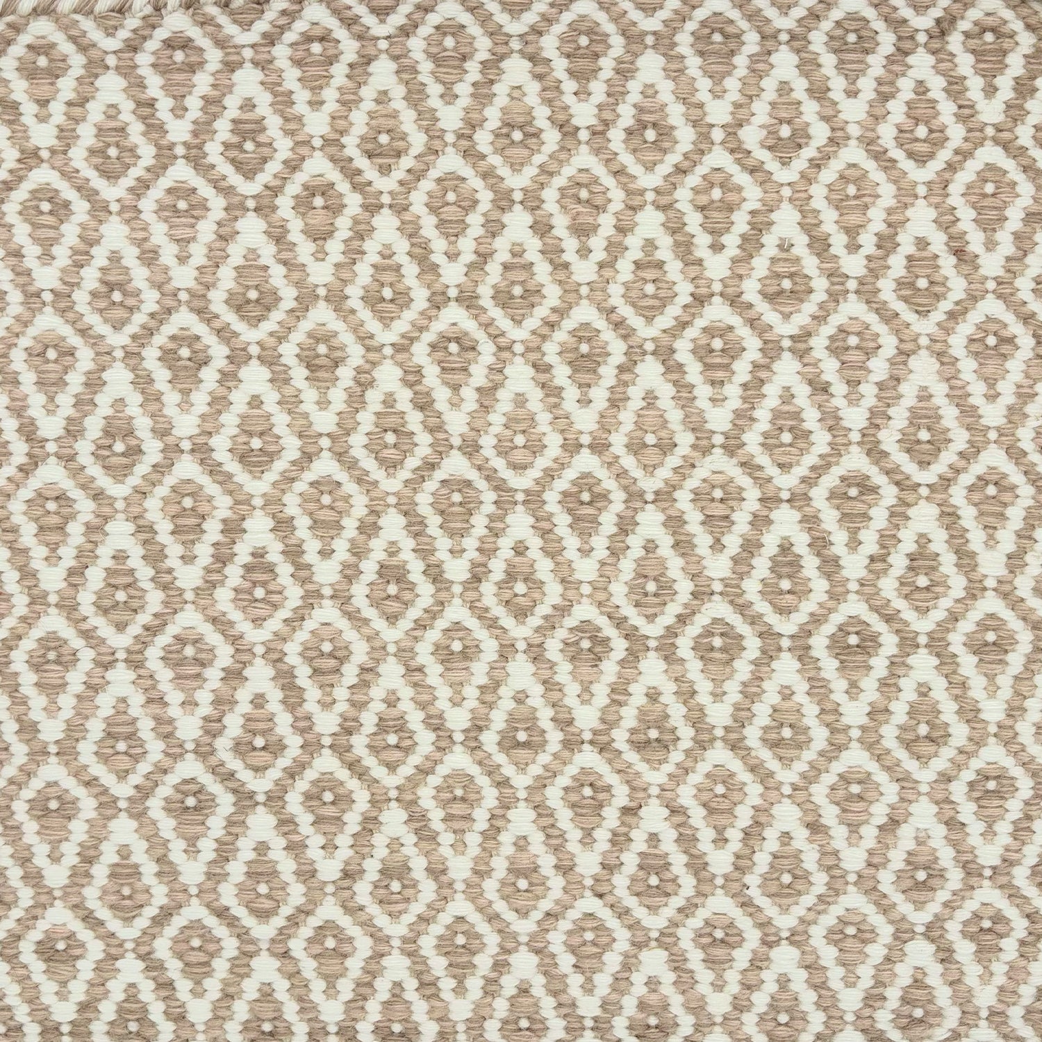 Detail of a handowven rug in an diamond like pattern in white and soft pink.