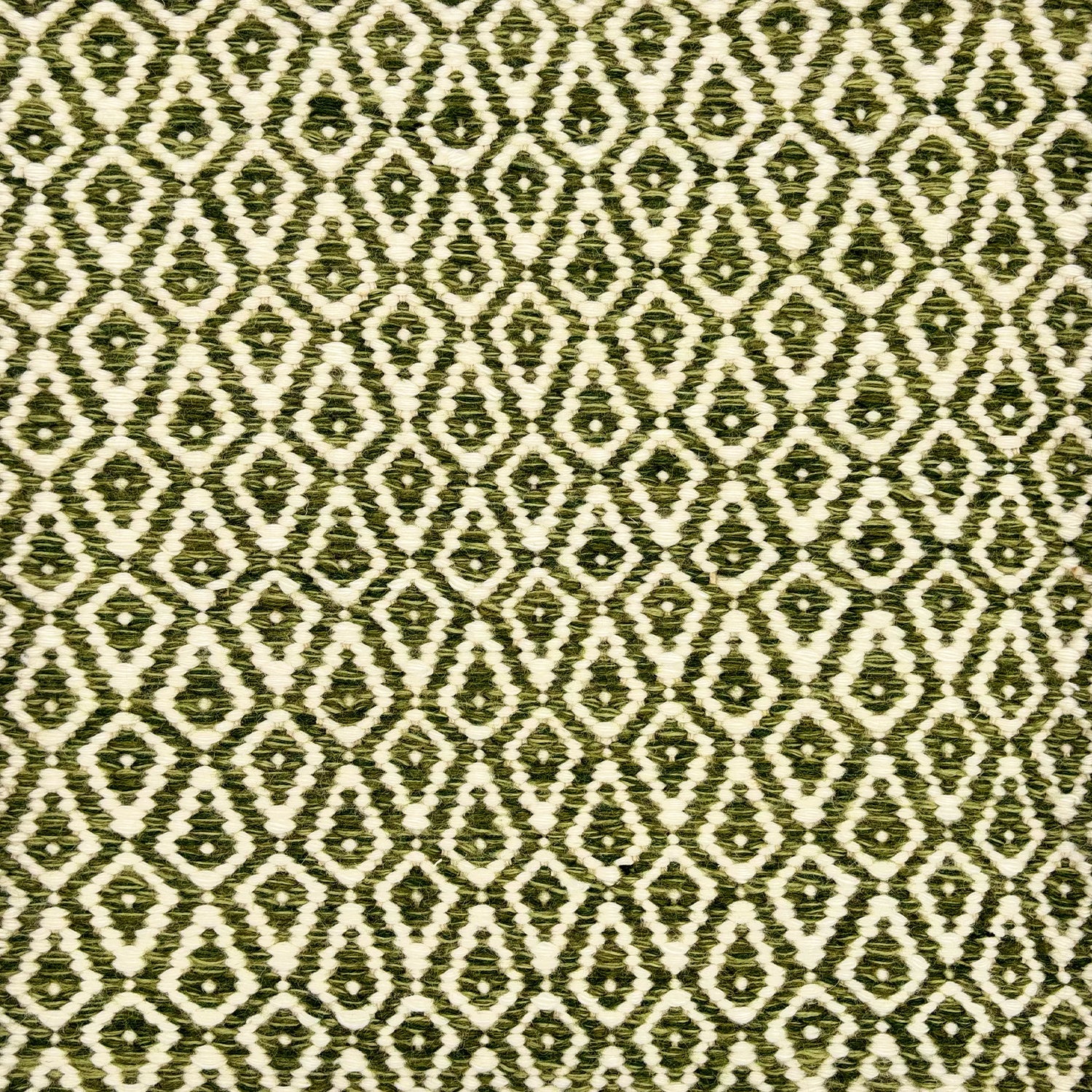 Detail of a handowven rug in an diamond like pattern in white and shades of green.