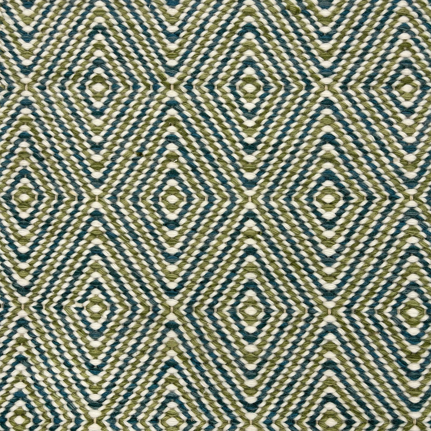 Detail of a flatwoven rug with a diamond pattern in white, blue and green.