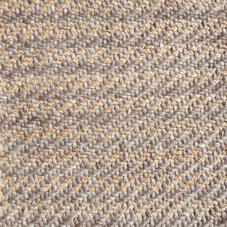 Detail of a textural rug in natural fiber and brown yarn.