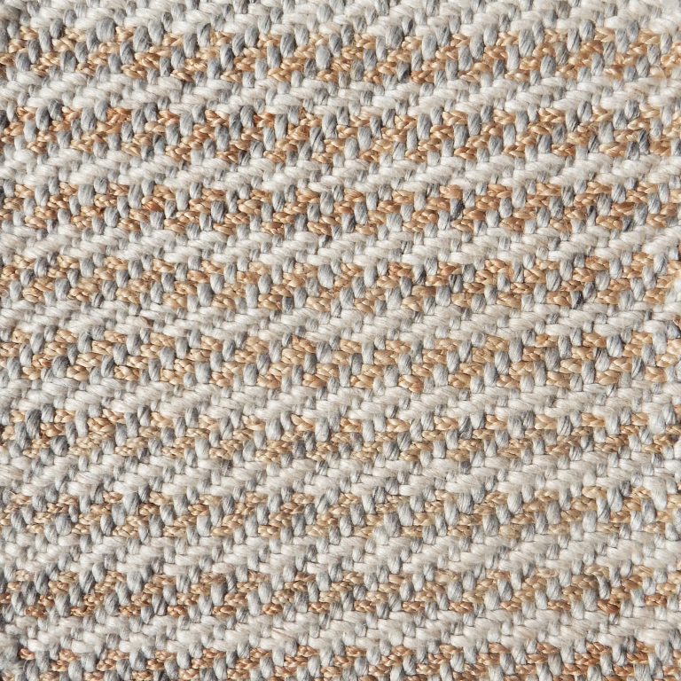 Detail of a textural rug in natural fiber and grey and white yarn.