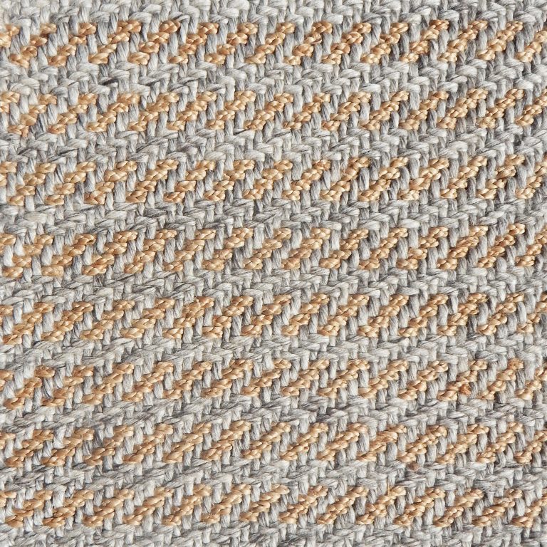 Detail of a textural rug in natural fiber and grey yarn.