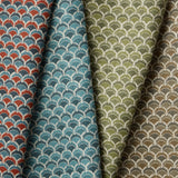 A row of four folded fabric swatches all in different colorways of the same Japanese-inspired scalloped pattern. 