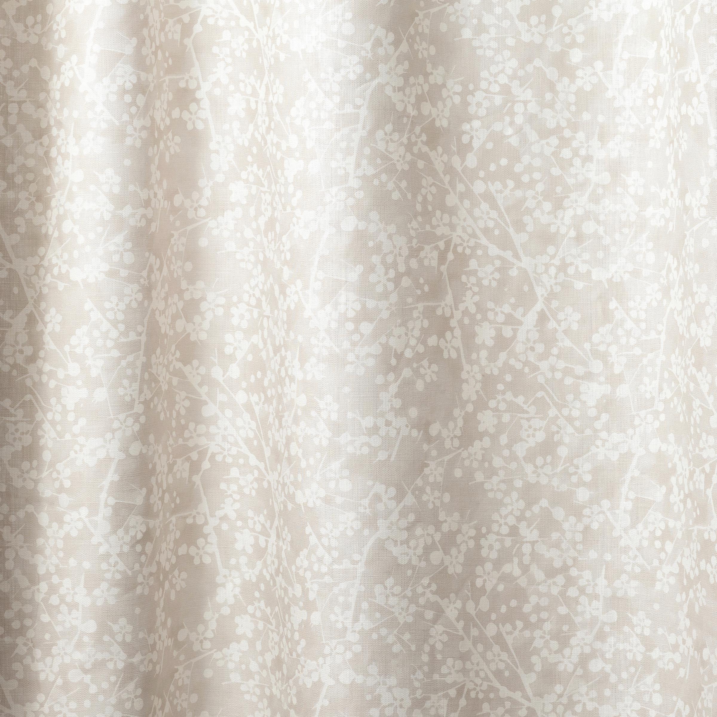 Draped fabric in a painterly branch print in white on an ecru watercolor field.