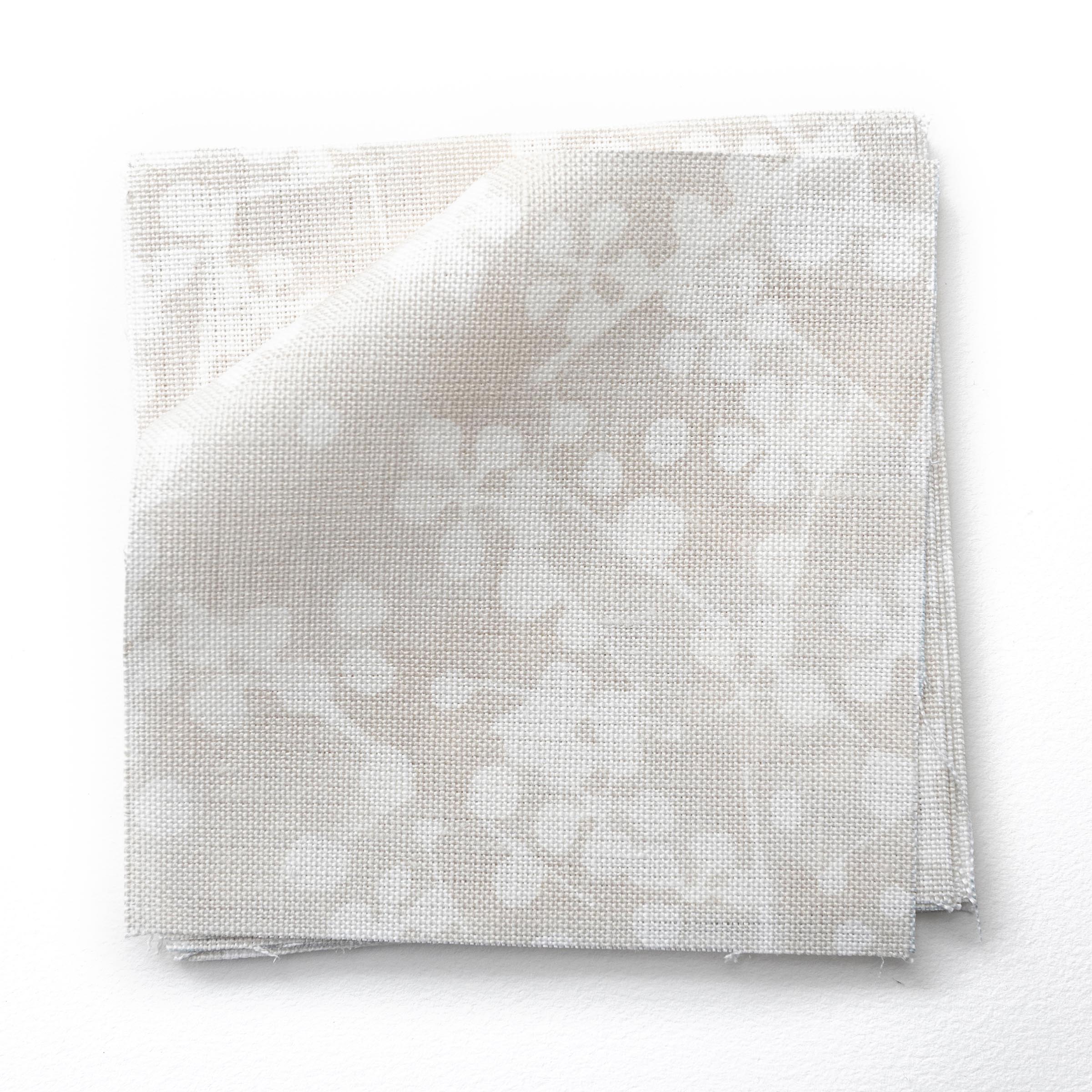 Fabric swatches in a painterly branch print in white on an ecru watercolor field.