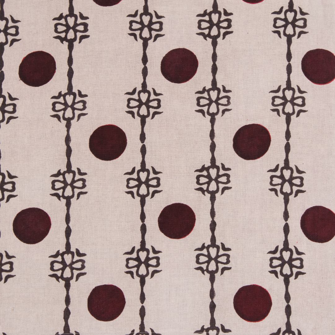 Detail of fabric in a linear flower and circle print in brown and dark green on a tan field.