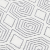 Detail of an embroidered fabric with a geometric spiral design in grey on a white field.