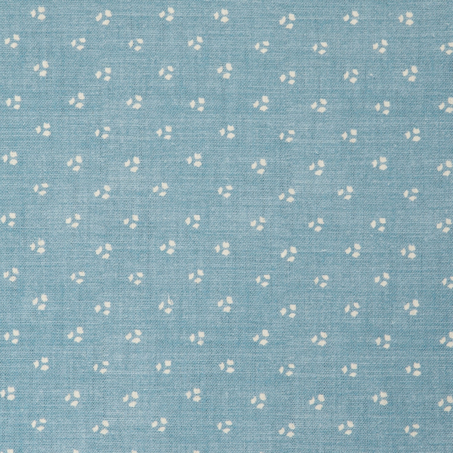 Detail of a linen fabric in a clustered dot pattern in cream on a sky blue field.
