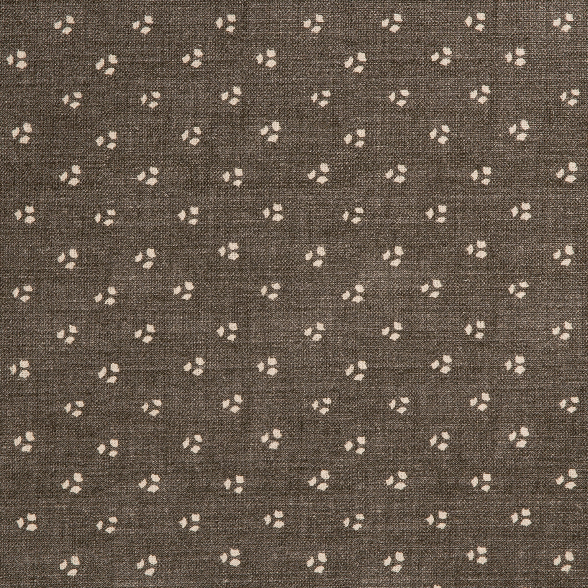 Detail of a linen fabric in a clustered dot pattern in beige on a dark gray field.