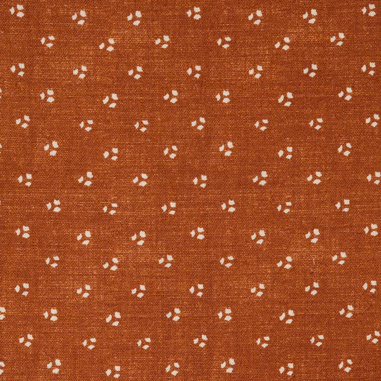 Detail of a linen fabric in a clustered dot pattern in beige on a burnt orange field.
