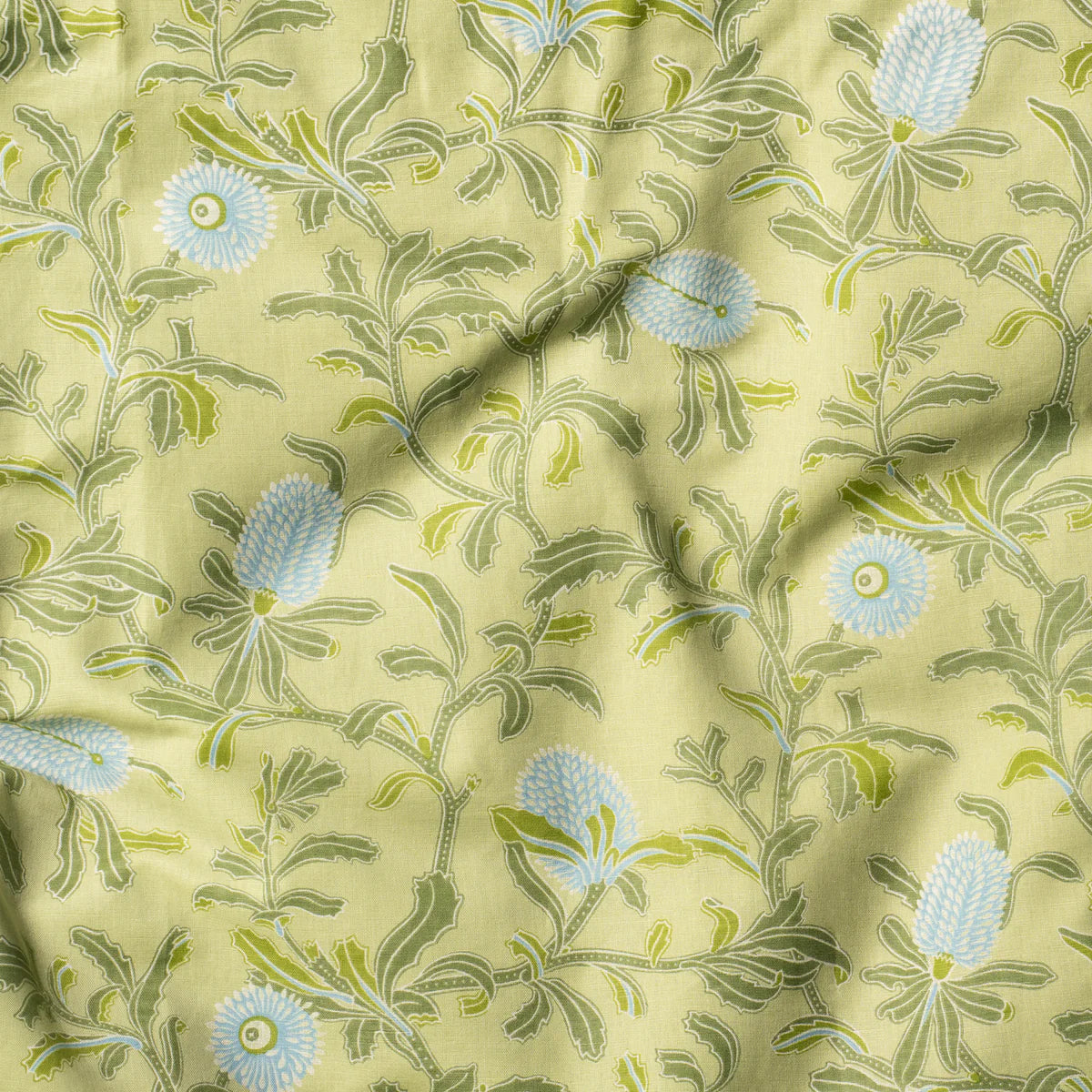 Draped fabric in a floral print in shades of blue and green on a yellow field.