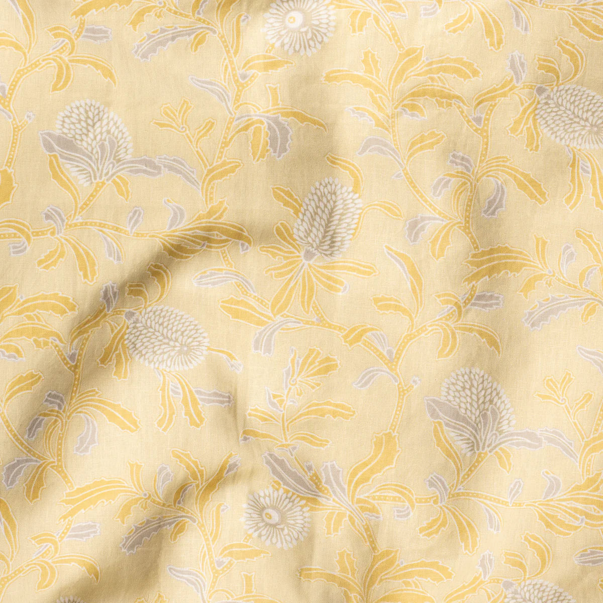 Draped fabric in a floral print in shades of gray and yellow on a light yellow field.
