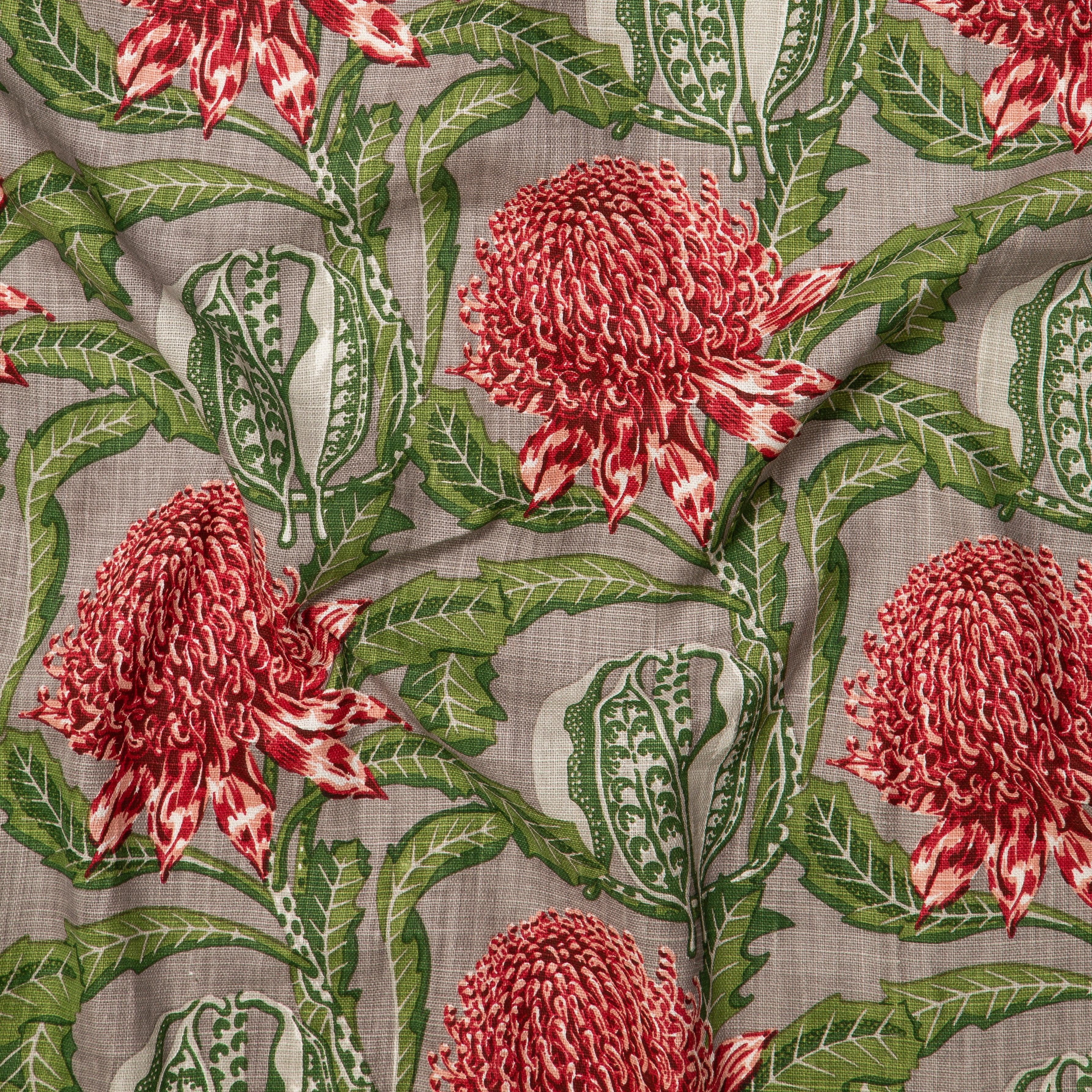 Draped fabric in a large-scale floral print in shades of green and red on a gray field.