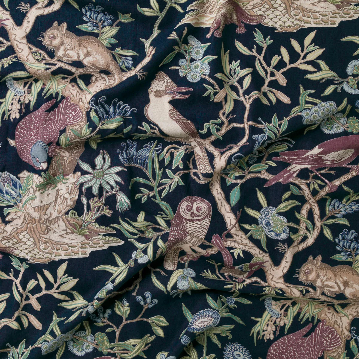 Draped fabric in an animal and tree branch print in brown, purple and green on a black field.