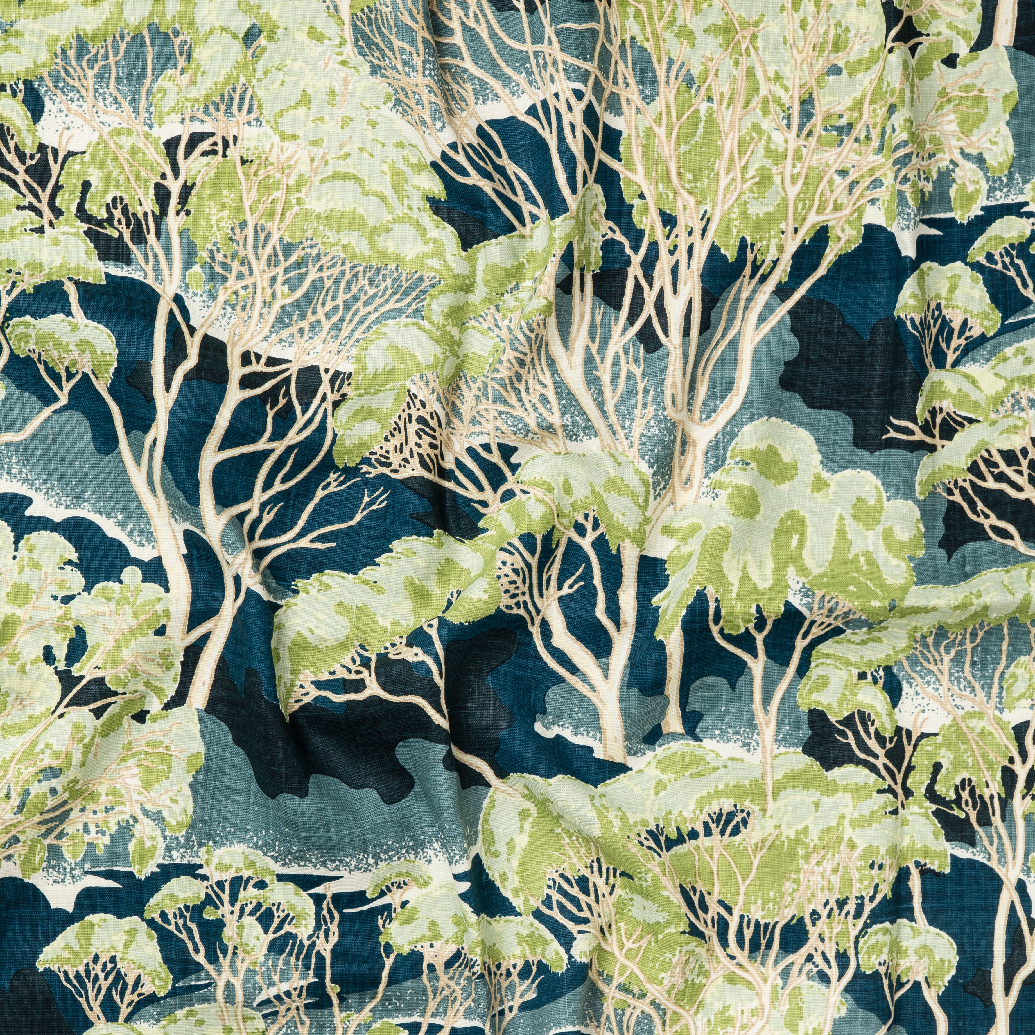Draped fabric in a painterly tree print in shades of cream and green on a navy field.