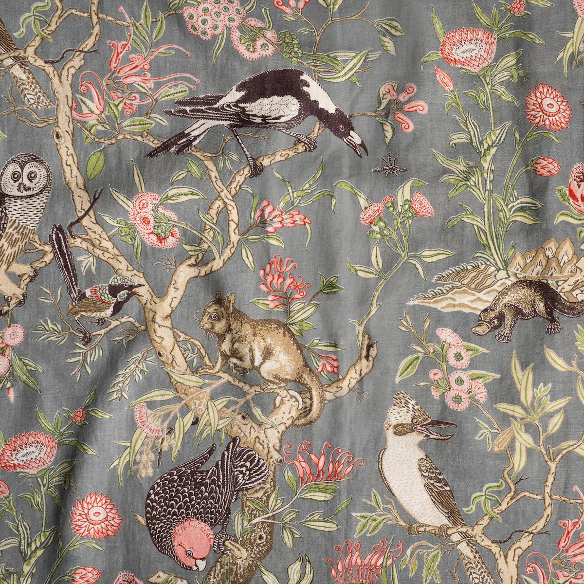 Draped fabric in an animal and tree branch print in brown, gray, red and green on a dark gray field.