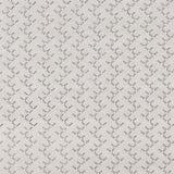 Panel of embroidered fabric in a linear geometric print in white and black on a cream field.