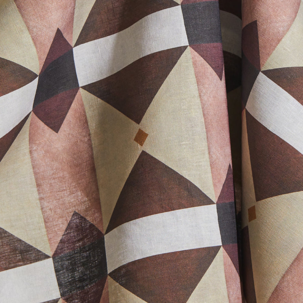 Draped fabric yardage in a large-scale geometric grid in shades of tan, purple and brown on a white field.