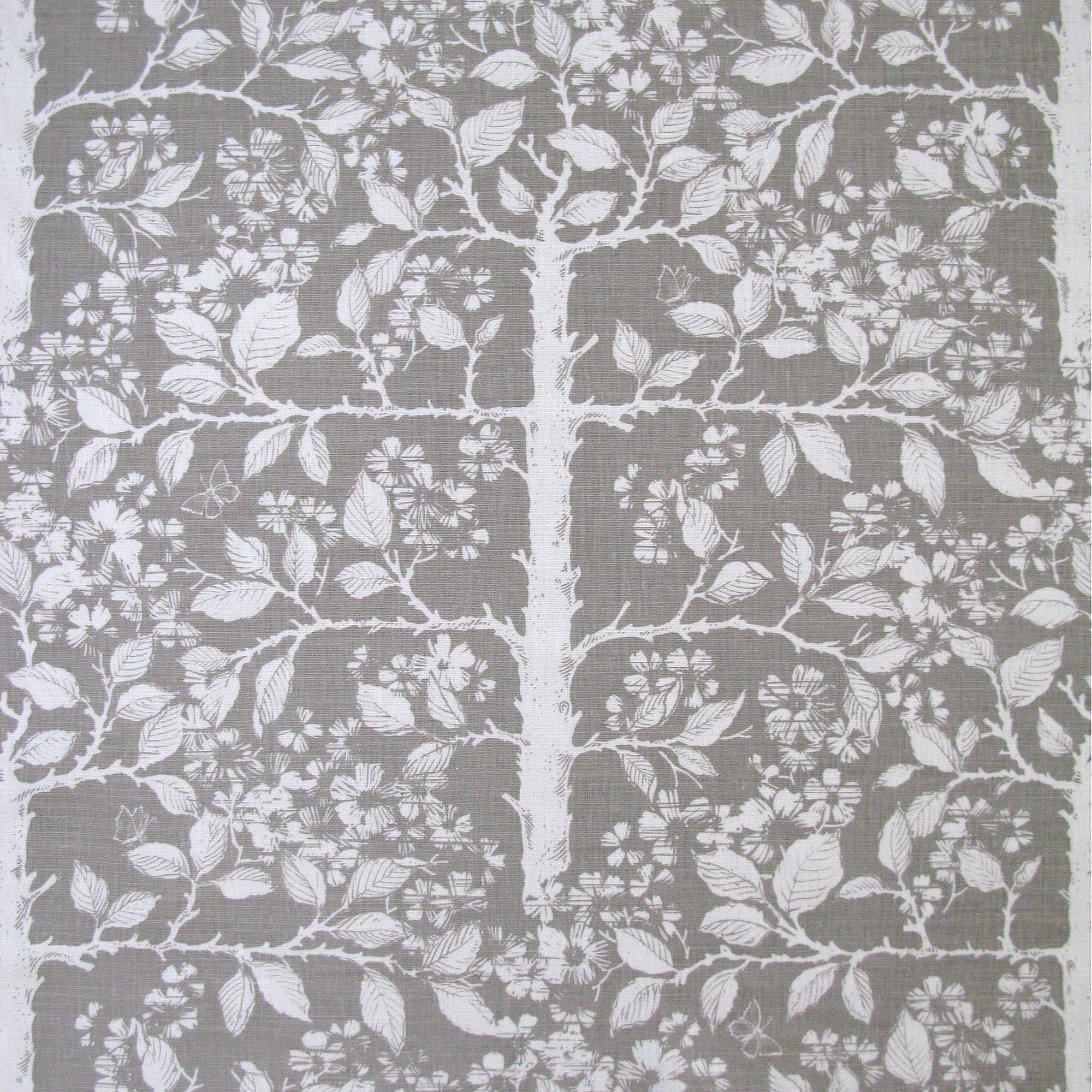 Detail of fabric in a large-scale tree and leaf print in white on a light gray field.