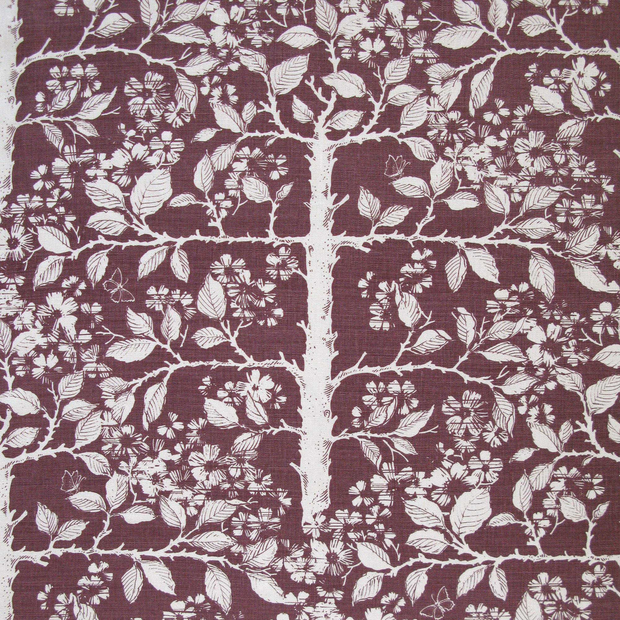 Detail of fabric in a large-scale tree and leaf print in cream on a maroon field.