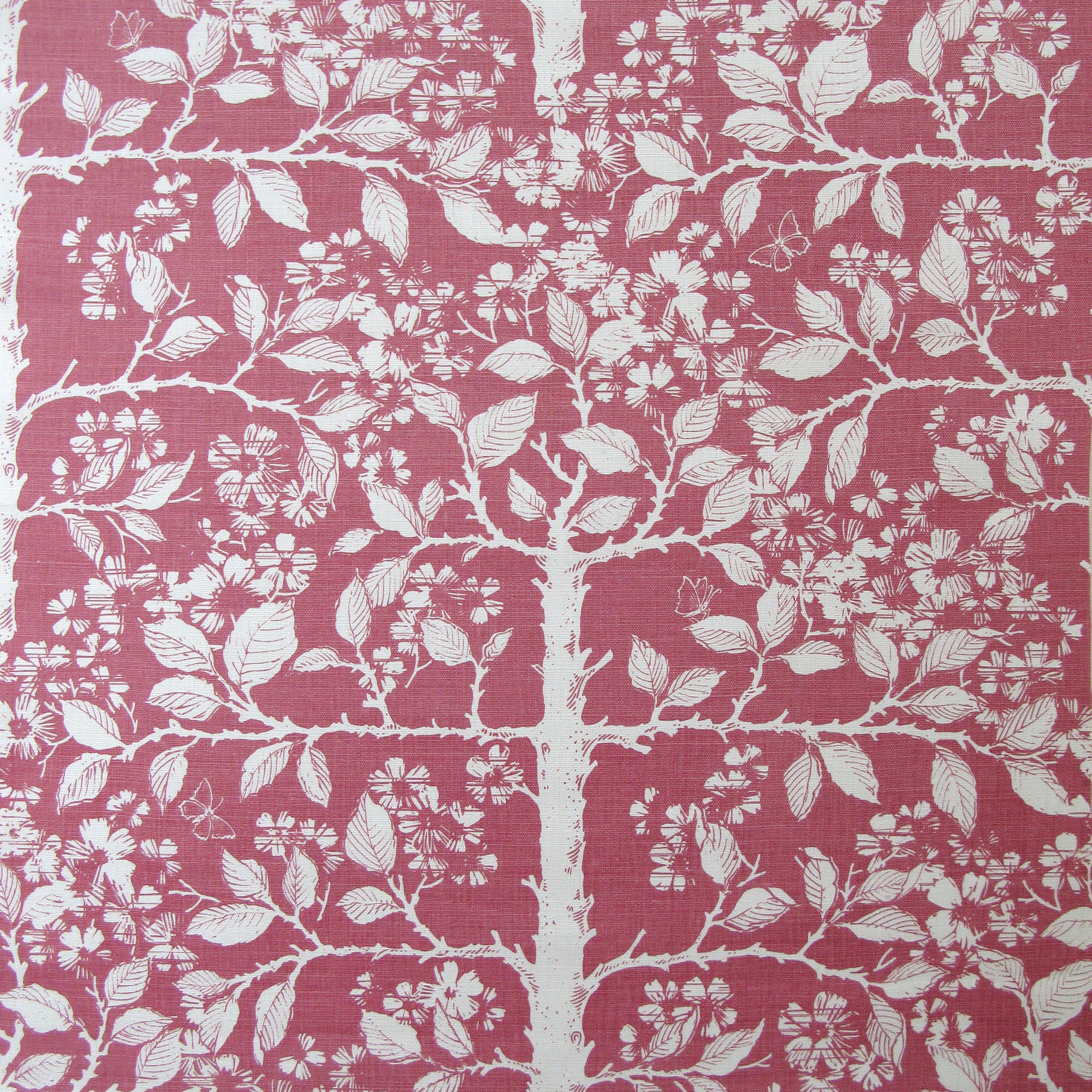 Detail of fabric in a large-scale tree and leaf print in cream on a pink field.