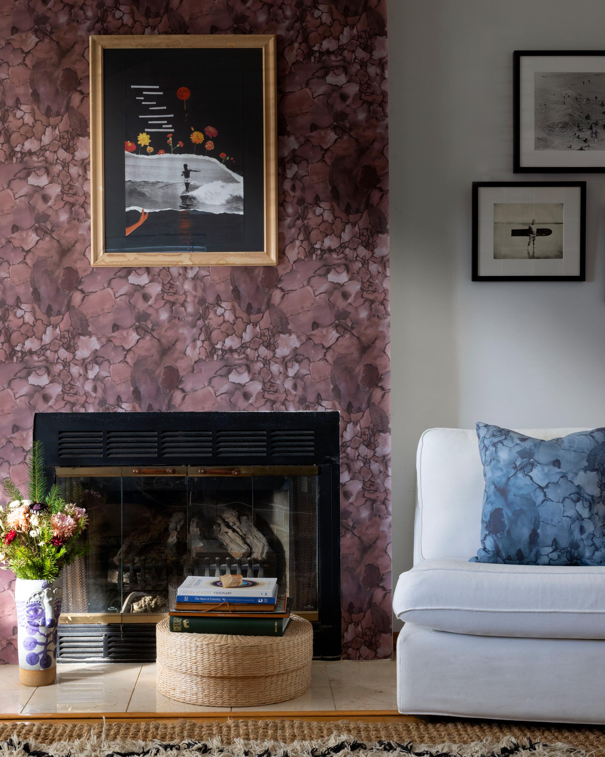 A maximalist living room tableau with a statement wall papered in an abstract textural print in red, gray and black.